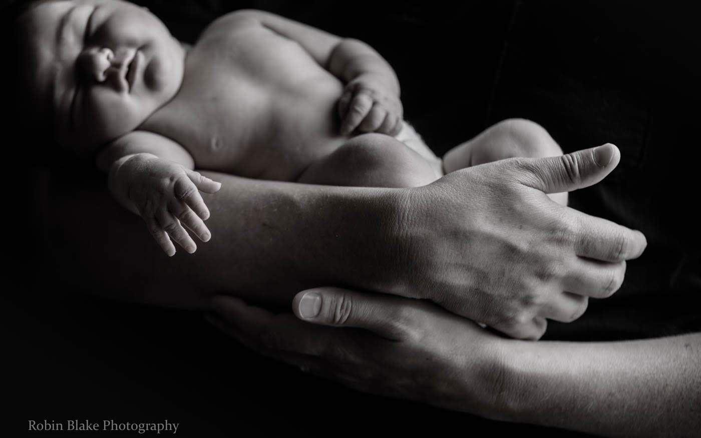 Larry's hands cradling his newborn daughter