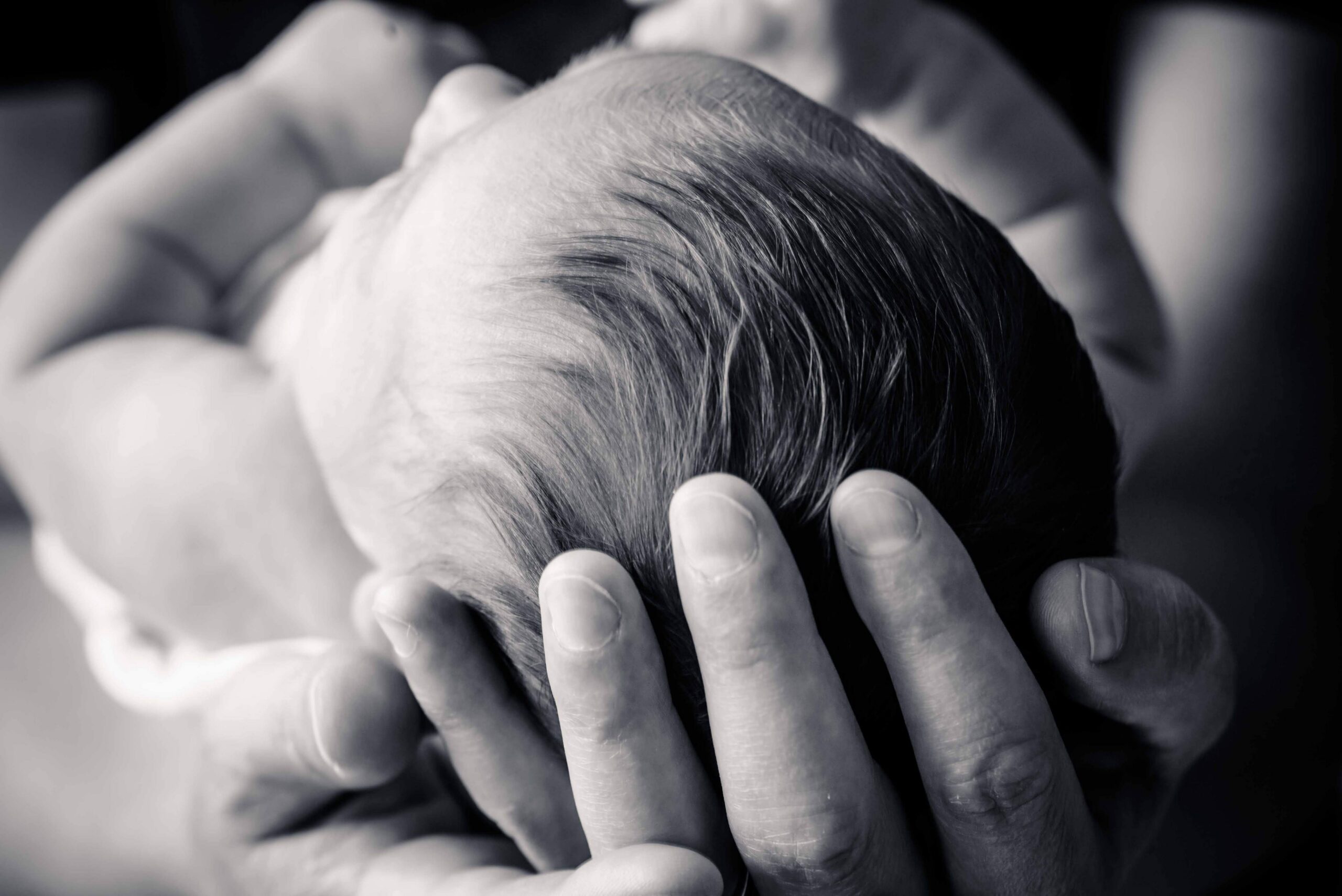 Larry's hand cradling his newborn daughter Ruby's head